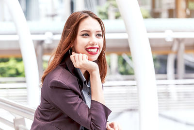 Smiling young businesswoman standing on elevated walkway 