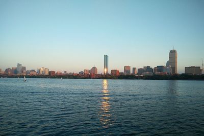 City skyline by river against clear sky