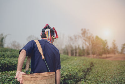 Man standing in basket on field against sky