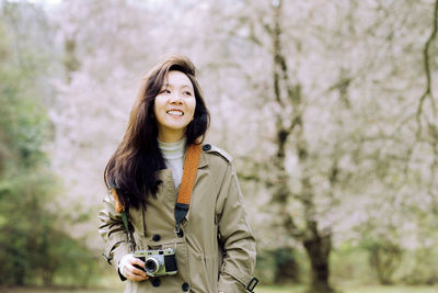 Young woman standing against trees