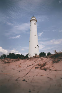 White lighthouse on beach against sky