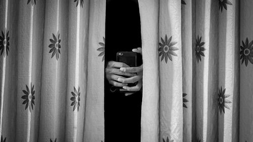Close-up of person photographing through curtain