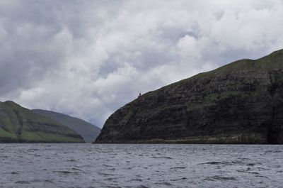 Scenic view of sea by mountains against sky