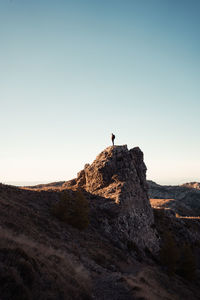 Man standing on rock against sky