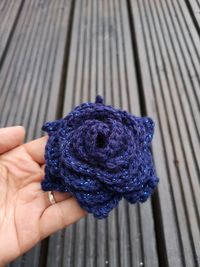 Cropped hand holding knitted wool flower over table