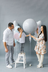 Gender reveal party. stylish beautiful family with a baby pop a balloon to find out the gender