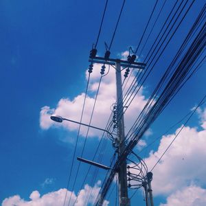 Low angle view of electricity pylon against blue sky