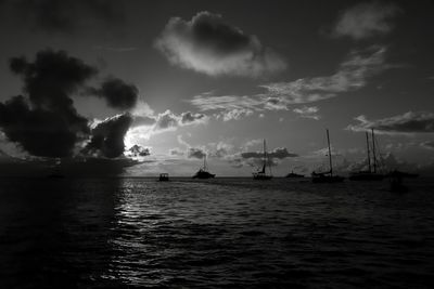 Silhouette sailboats in sea against sky during sunset