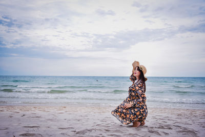 Woman with umbrella on beach against sky