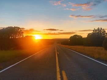 Empty road against sky during sunset