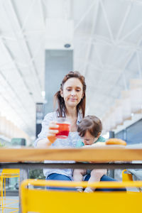 Mother carrying son sitting at shopping mall