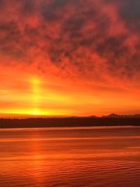 Scenic view of lake against dramatic sky during sunset