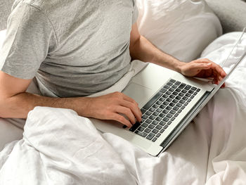 Man using laptop at home in bed vibes freelancer, freelance job, using technology using social media