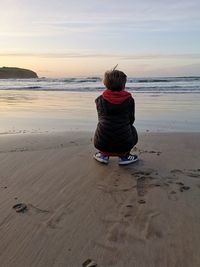 Rear view of woman sitting on beach