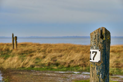 Wooden post on field against sky