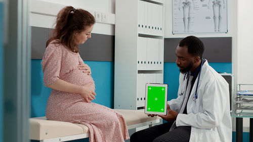 Side view of young woman using mobile phone while sitting in hospital