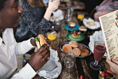 High angle view of man eating burger while sitting with female friends at restaurant