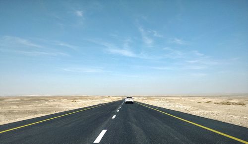 Road passing through land against sky