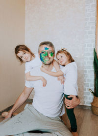 Father with painted face playing with daughter at home