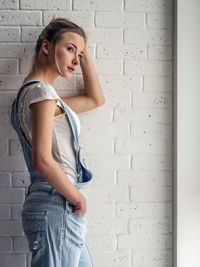 Young woman looking away standing against wall