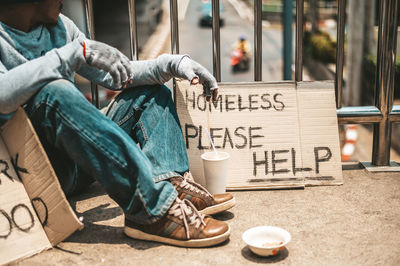 Midsection of man sitting on street in city