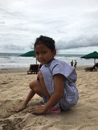 Portrait of boy sitting on beach against sky