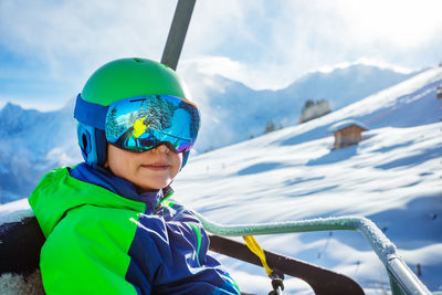 Rear view of boy standing on snow covered mountain against sky