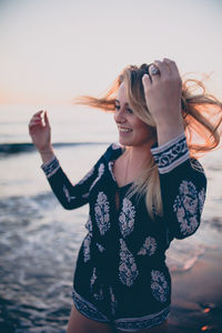 Smiling young woman standing at beach