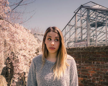 Portrait of beautiful young woman standing against sky