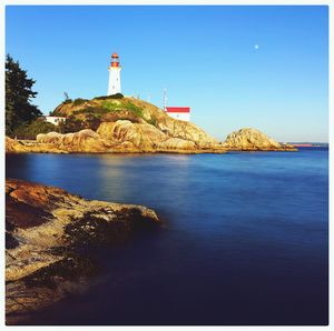 Lighthouse in sea against blue sky