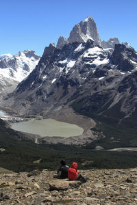 Rear view of people on snowcapped mountain against sky