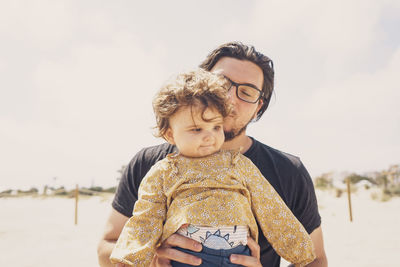 Father and son on shore against sky