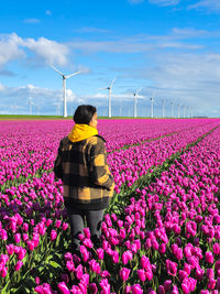 Rear view of woman standing amidst flowers