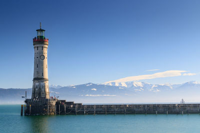 Lighthouse by sea against sky