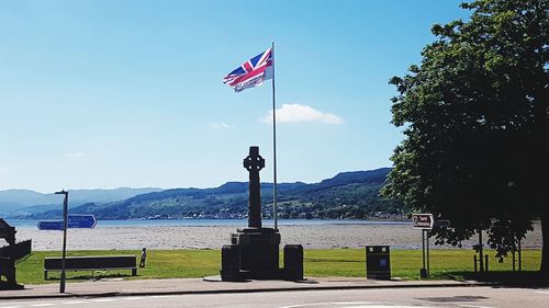 Scenic view of flag by trees against blue sky