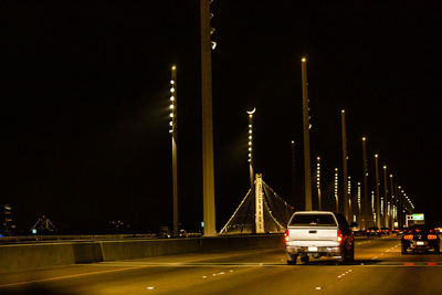 Cars on bridge against sky in city at night