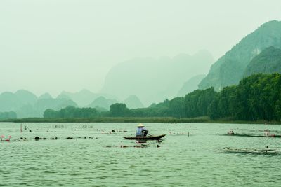 Man on boat in river against mountains