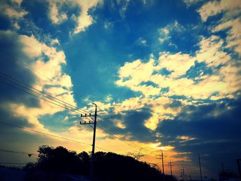 Low angle view of electricity pylon against cloudy sky