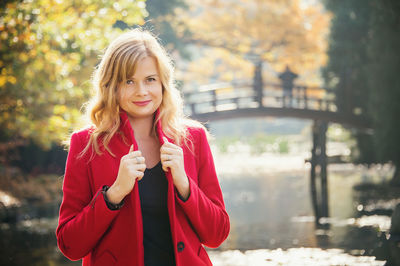 Young attractive woman wearing in red coat in autumn city park