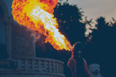 Rear view of man with fire crackers against sky