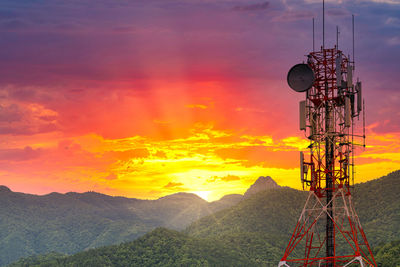 Low angle view of communications tower against orange sky
