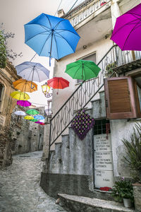 Low angle view of multi colored umbrellas hanging on building