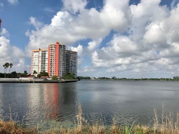 Buildings by lake against sky in city