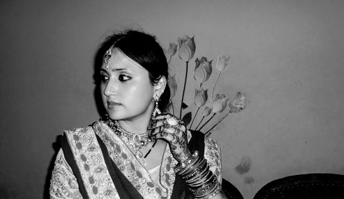 Bride looking away while sitting against wall at home