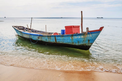 Boat moored on shore against sky