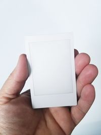 Close-up of hand holding paper against white background