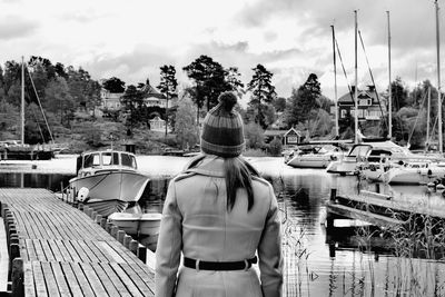 Rear view of woman standing on sailboat against sky