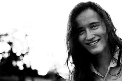 Portrait of smiling man with long hair against sky