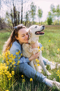 Portrait of young woman with dog on field