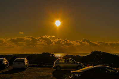 Cars on road against sky during sunset